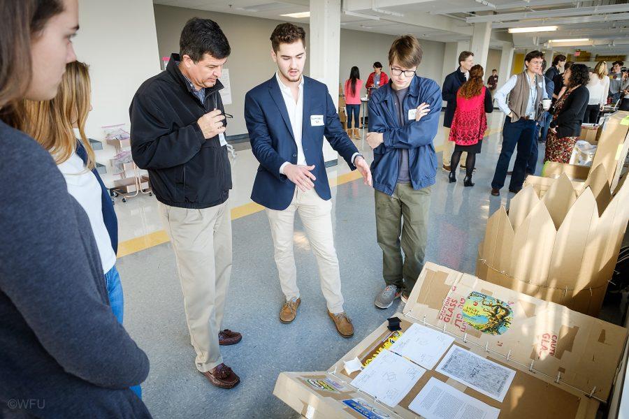 Wake Forest students in Engineering 111 hold a Project Expo to display their work during the semester, including chairs made from cardboard, at Wake Downtown, on Tuesday, December 12, 2017. Garrett Odell ('21) talks about his project with Richard Eskridge from Duke Energy.