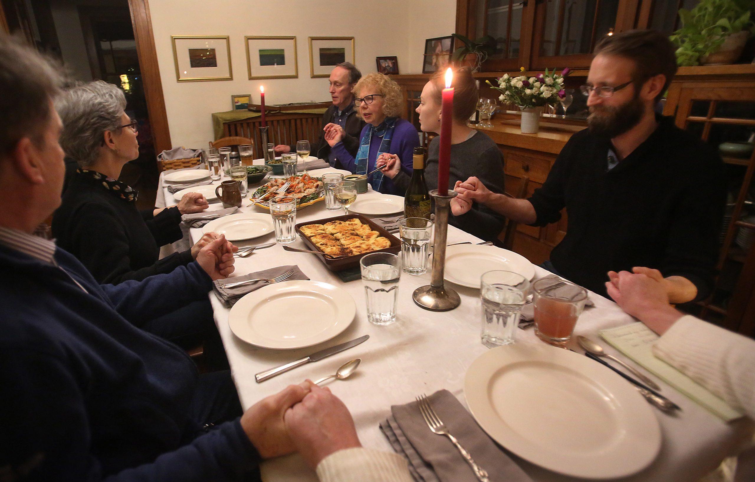 Ann Luce, back row, second from left, begins the dinner with prayer on Jan. 26, 2018 in Minneapolis, Minn. Two families, their children and occasionally their friends have been dining together weekly for about 30 years. (David Joles/Minneapolis Star Tribune/TNS)
