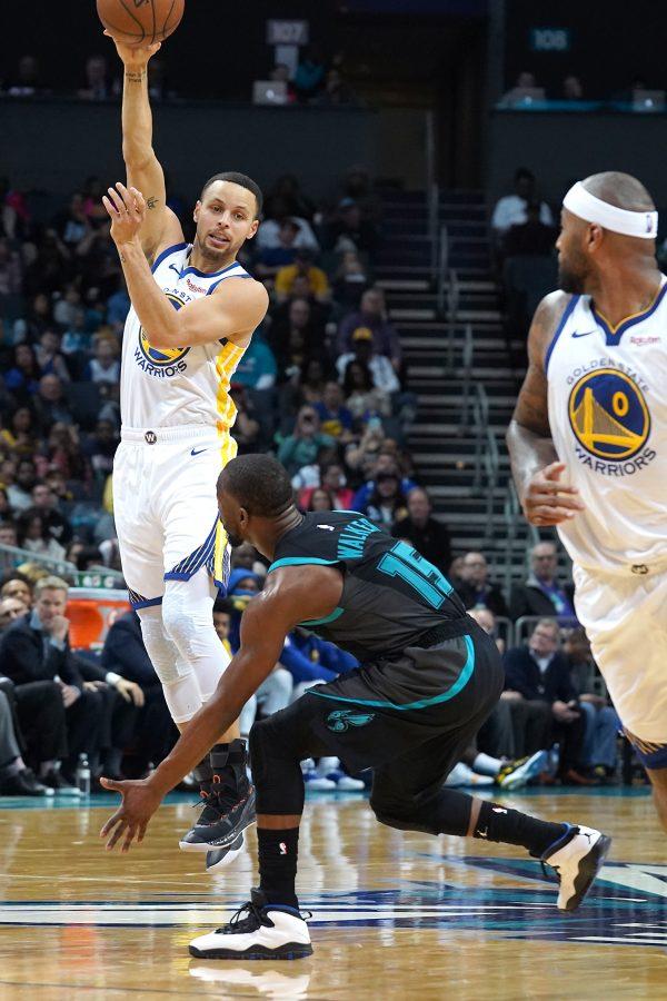 Golden State Warriors guard Stephen Curry, left, passes over Charlotte Hornets guard Kemba Walker, center, to center DeMarcus Cousins, right, during second half action Monday, Feb. 25, 2019 at Spectrum Center in Charlotte, N.C. (Jeff Siner/Charlotte Observer/TNS)