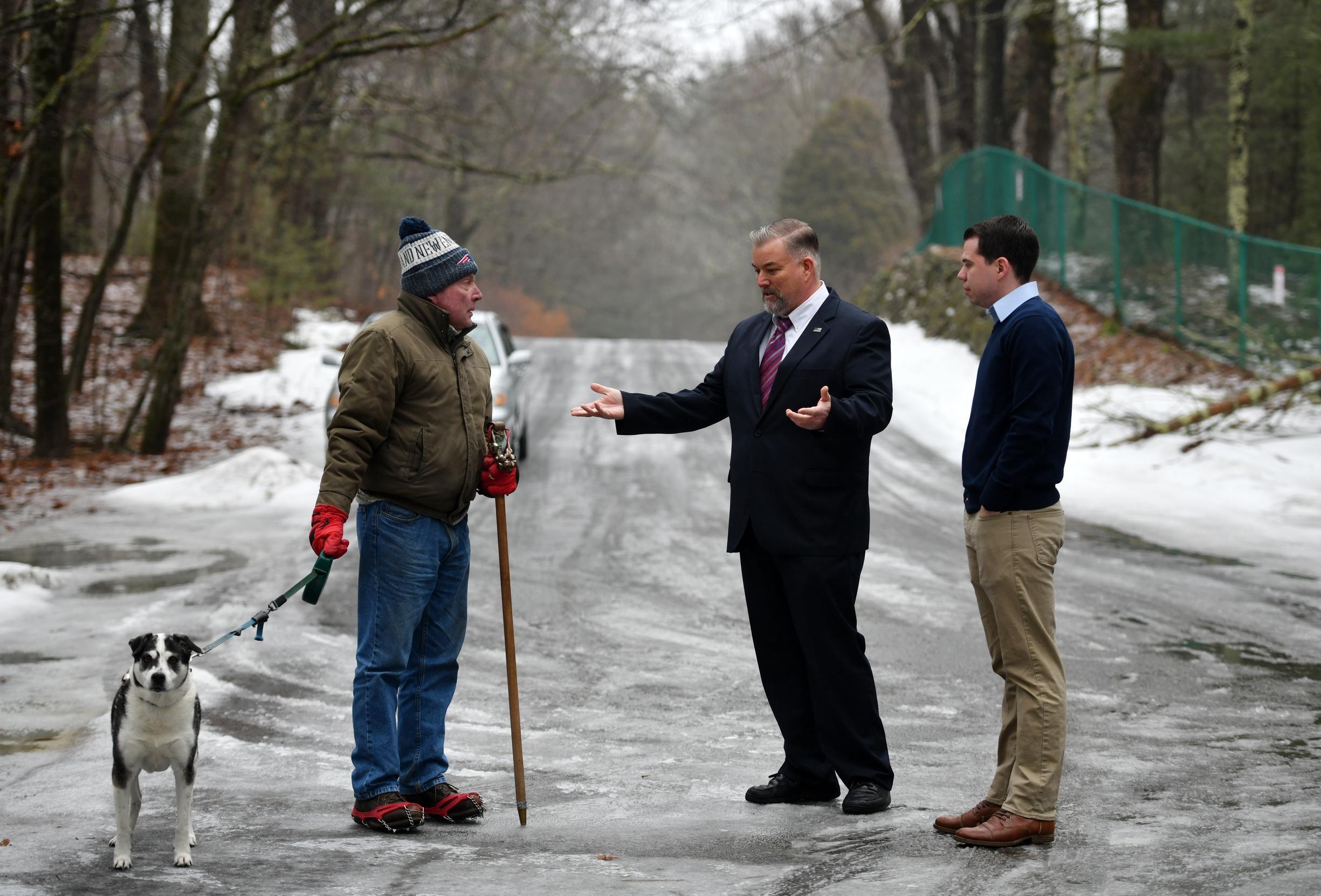 Patrick Culhane of Worcester holds his dog Mias leash as he talks with Town Adminstrator Mike Nicholson and Rutland Selectman Jeff Stillings near a closed gate in the trail system in Rutland State Park on Tuesday. [T&G Staff/Christine Peterson]