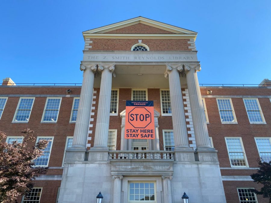 A sign reminding students of the university’s Orange operating status hangs between the pillars of the Z. Smith Reynolds Library (Maddie Sayre/Old Gold & Black)