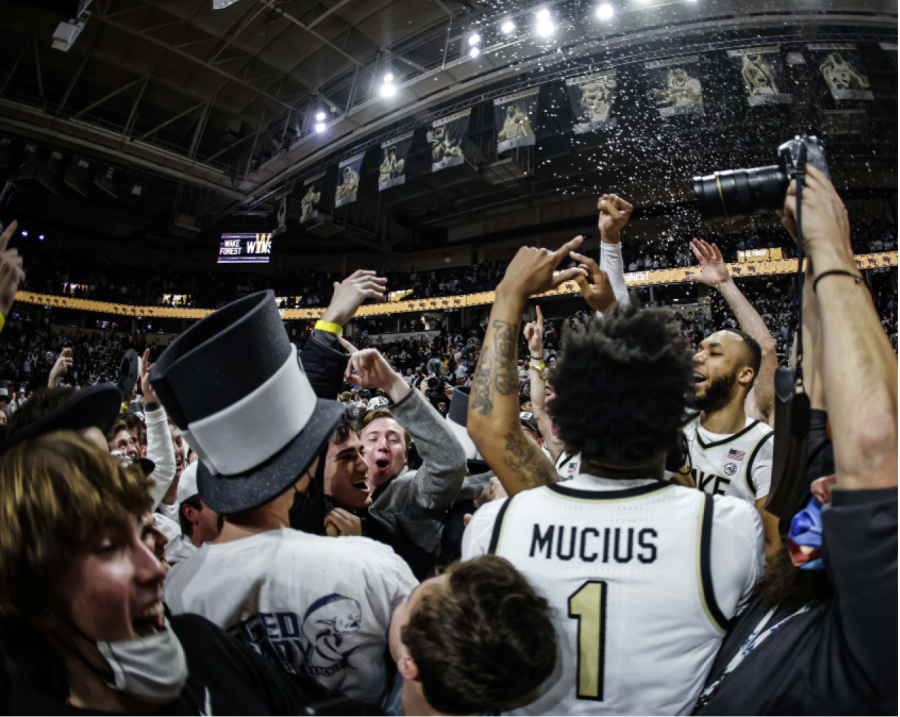 A photograph of students and players celebrating on a basketball court.