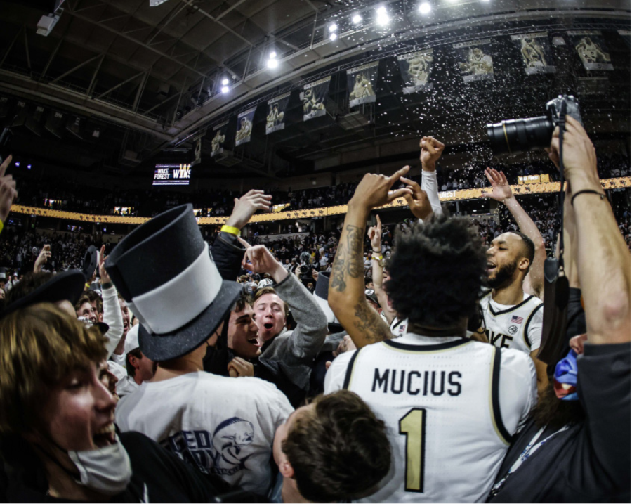 A+photograph+of+students+and+players+celebrating+on+a+basketball+court.