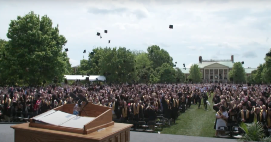 The Class of 2022, newly-graduated, throw their caps in the air.