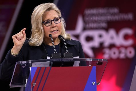 A photograph of Liz Cheney speaking behind a lectern. In the background, the logo for the 2020 Conservative Political Action Conference is visible.