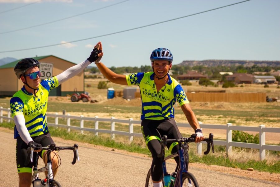 A photograph of two bikers hi-fiving