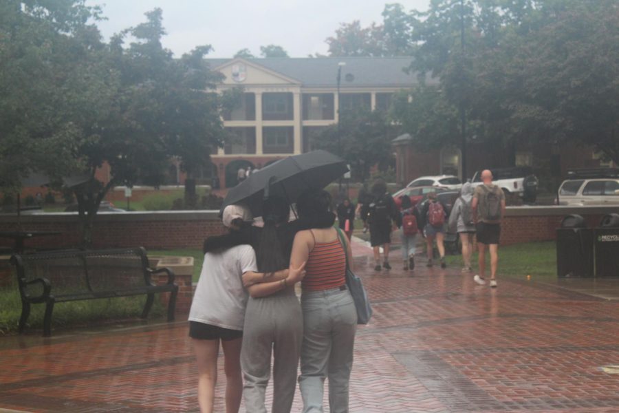 Students huddle under an umbrella as rains hit Winston-Salem on Friday.