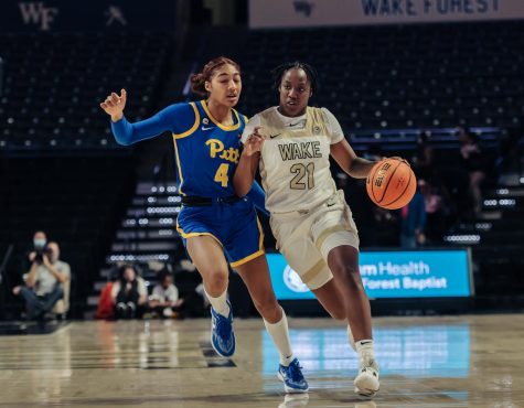 Elise Williams (no. 21 in white) dribbles past a Pitt defender.