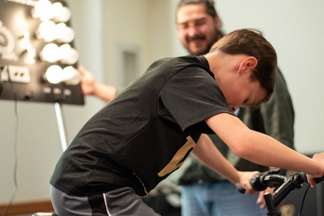 A student rides a stationary bike during the read-in event.