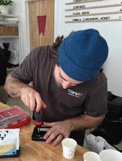 Kylan Reasoner repairs the broken scale that weighs the espresso machine coffee grounds.