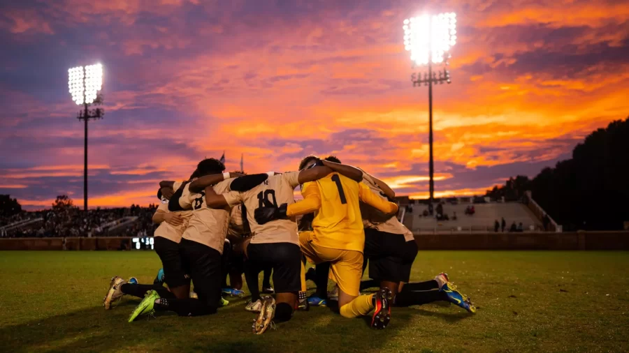 The mens soccer team huddles on the field at Spry Stadium.