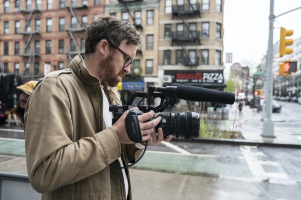 John Wilson stands in New York with his camera.