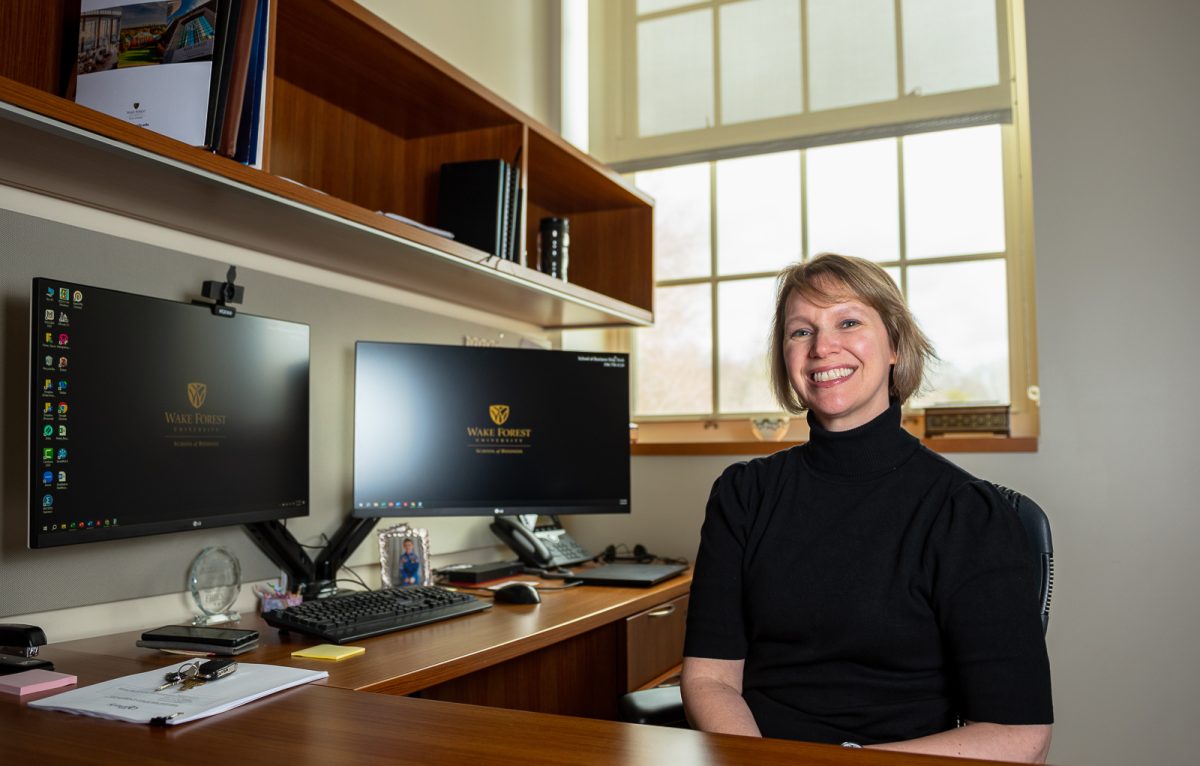 Stacie Petter, professor of management information systems at the Wake Forest School of Business, posed next to her computers in her office. Petter and her team received $1 million in funding from the National Science Foundation.