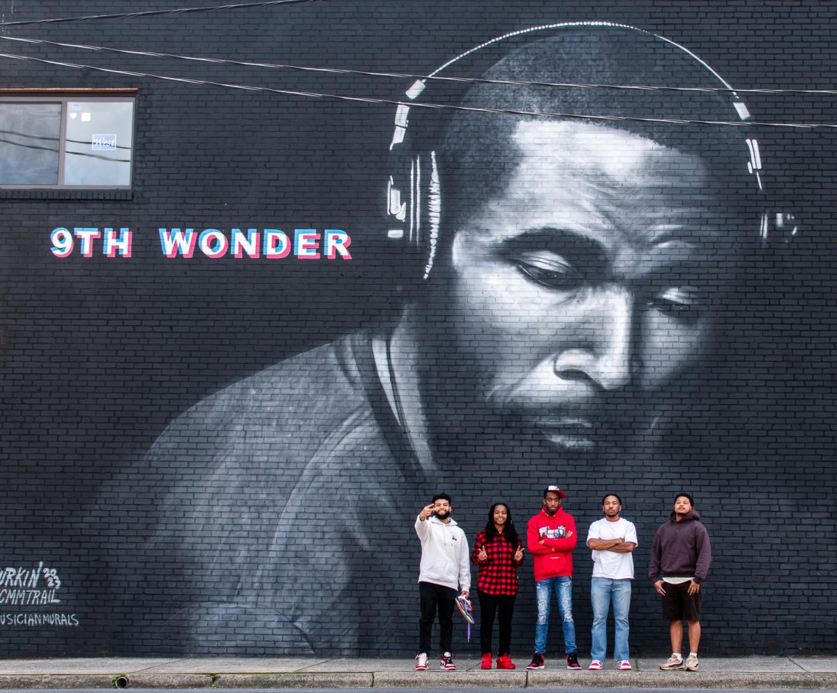 Members of the Salem Assassins (left to right: Dimarvin Puerto, Jada Douthit, El Awkward, Cameron French, Kobe Mccullough) stand in front of the 9th Wonder mural on 6th and Trade Streets.