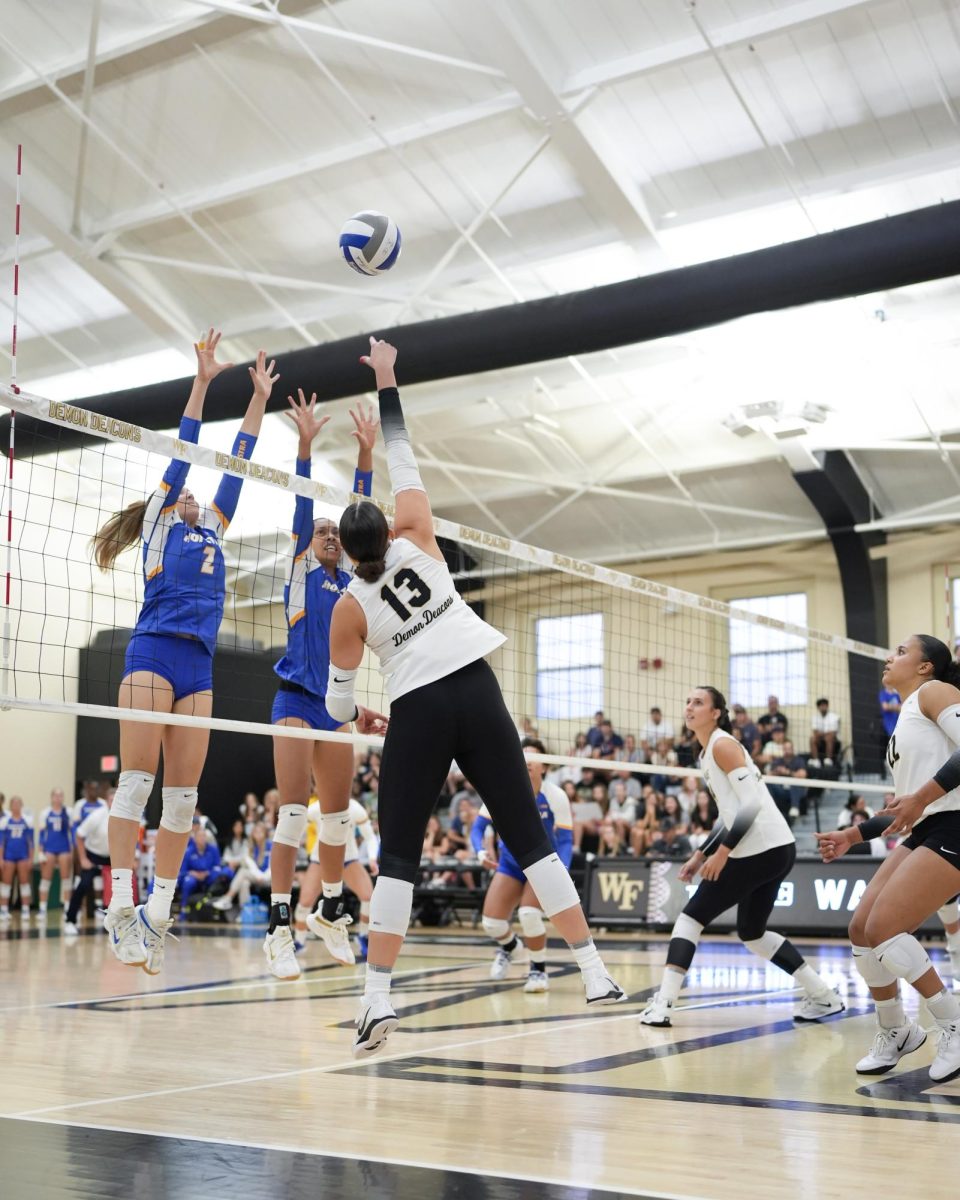 Wake Forest junior and outside hitter Paige Crawford (13) elevates to try sending the ball over two Hofstra defenders.