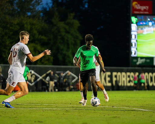 Wake Forest midfielder Babacar “Baba” Niang dribbles ahead of an Elon defender during Tuesday night’s match. Niang scored the Demon Deacons’ single goal of the evening.