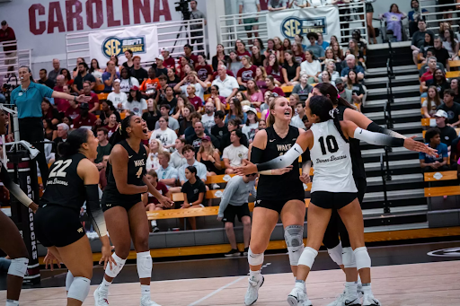 Wake Forest’s Sahara Maruska (22), Laila Ricks (4) and Emma Farrell (10) celebrate with teammates during Friday’s victory over Florida International University. Ricks recorded a career-high number of kills in Friday's match. (Courtesy of Wake Forest Athletics) 
