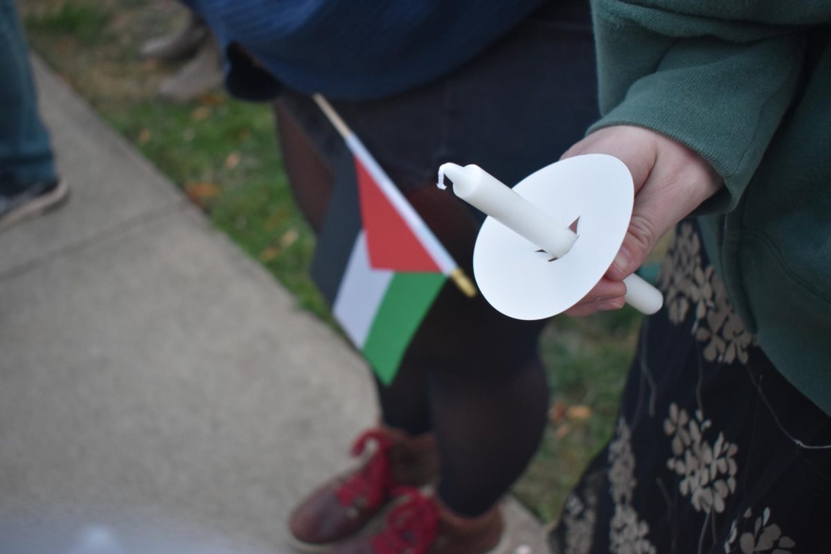 Two attendees at the Prayers for Peace Vigil hold a candle and a Palestinian flag. 