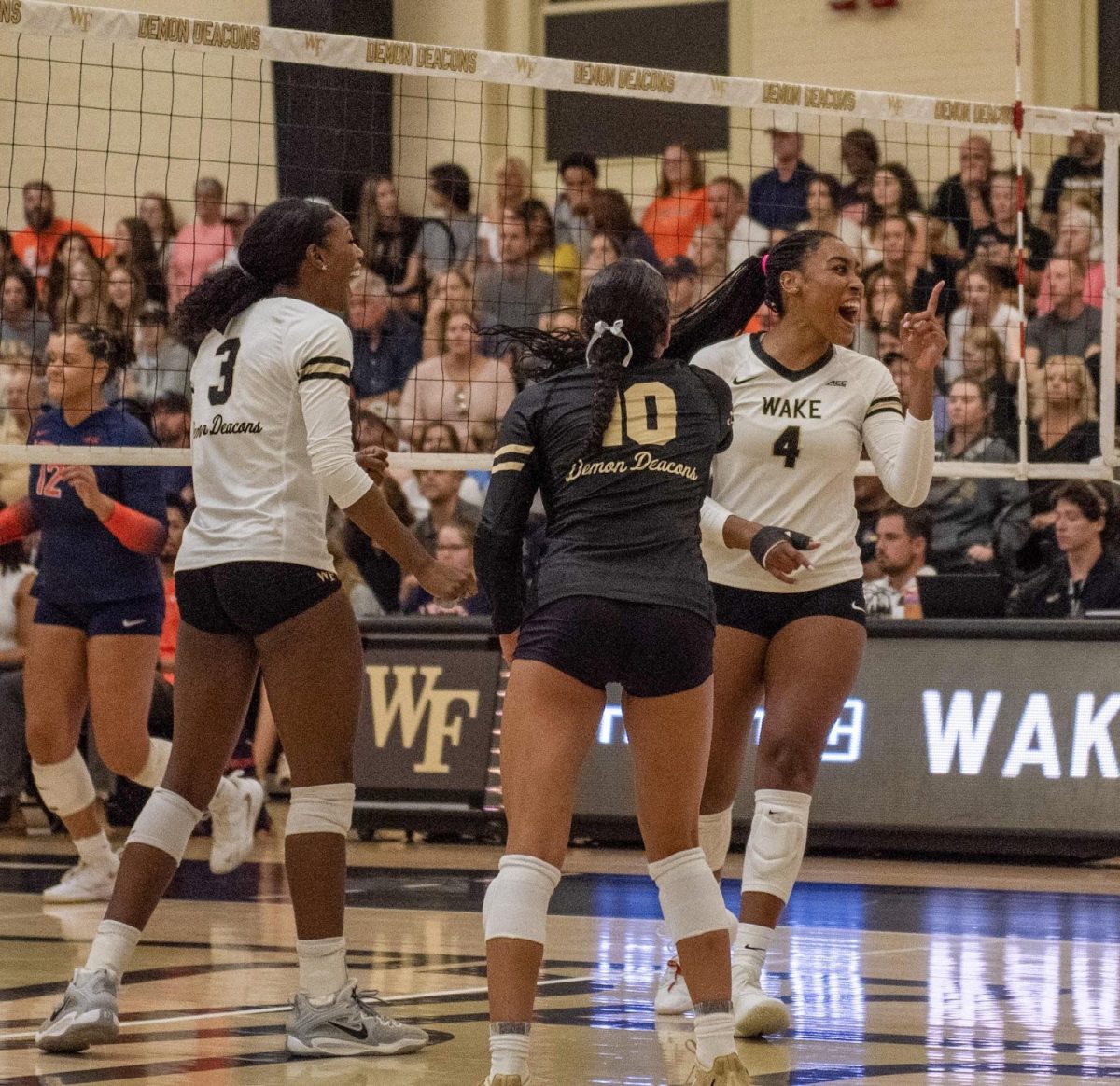 Wake Forest’s Dior Charles (3), Emma Farrell (10) and Laila Ricks (4) celebrate after a thrilling kill by Ricks during Friday evening’s match against the Virginia Cavaliers.