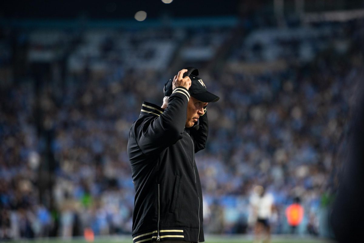 Wake Forest Head Coach Dave Clawson adjusts his headset as the Deacons prepared for an offensive drive after a timeout.