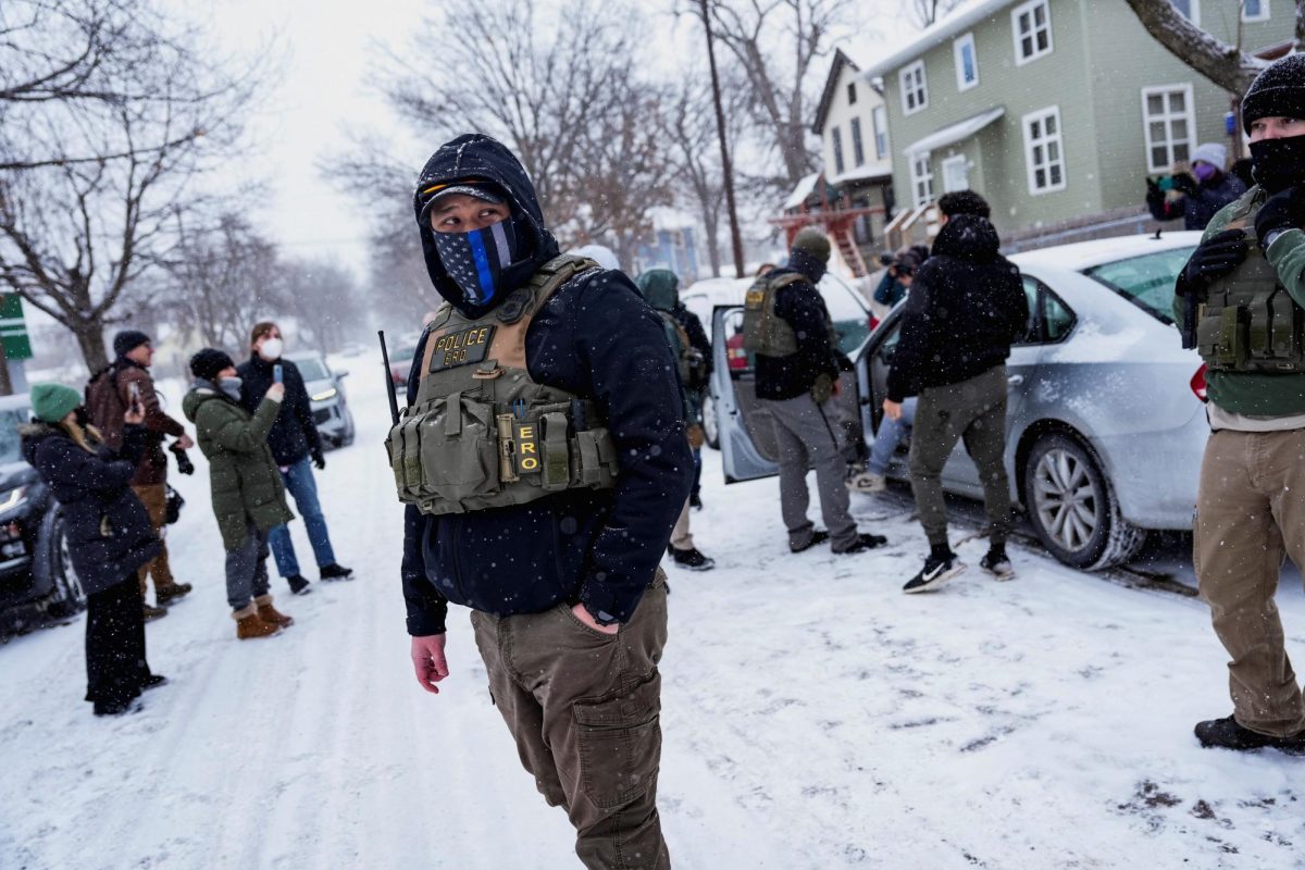 A member of the Enforcement and Removal Operations of ICE stands guard while a man is detained by Immigration and Customs Enforcement (ICE) agents during an immigration raid, days after an ICE agent fatally shot Renee Nicole Good, in Minneapolis, Minnesota, U.S., January 18, 2026.