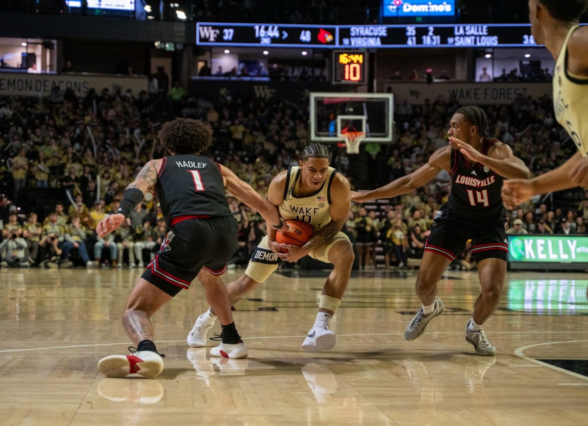 Sebastian Akins (10) gathers the ball into his chest as he steps between two defenders.