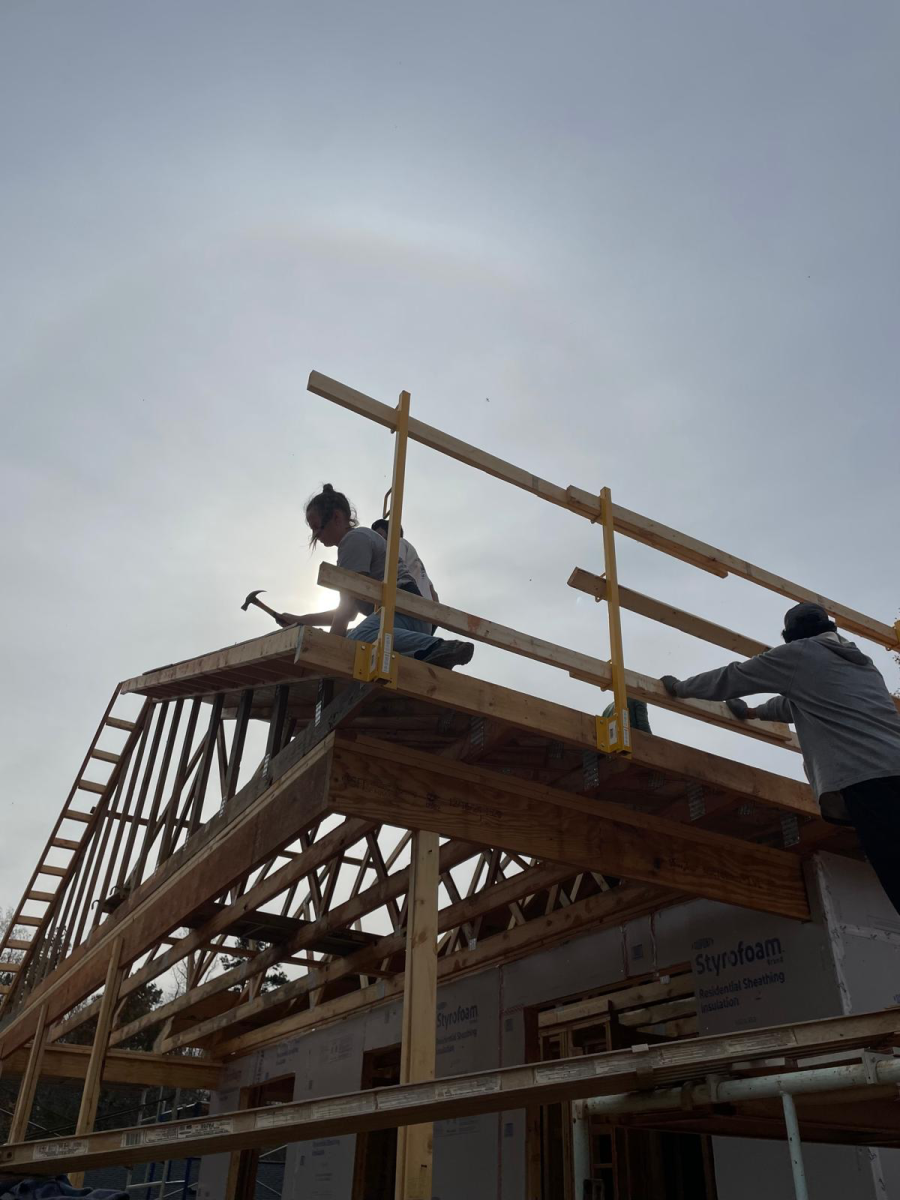 Mary Hauser (holding hammer) helps construct a roof at a Habitat for Humanity building project in Winston-Salem.