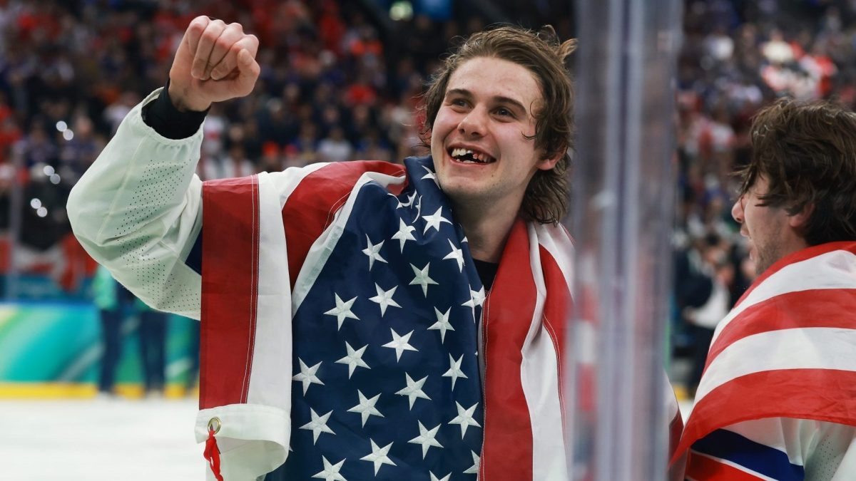 Left-handed forward Jack Hughes is seen wrapped in an American flag, celebrating his overtime goal against Canada that delivered the United States the Gold medal in Milan. (Photo courtesy of the NHL)
